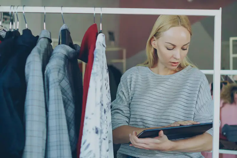 Encargada de una tienda de ropa revisando el inventario en una tableta