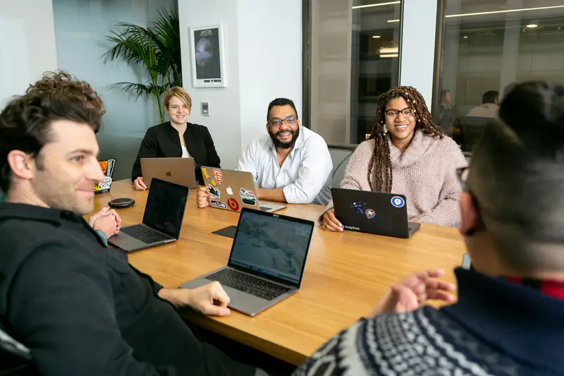 Equipo de trabajo en una reunión con laptops alrededor de una mesa